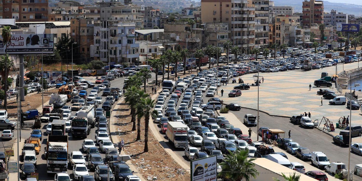 Bilköerna ringlar långa när civila libaneser flyr Israels attacker, här i Sidon söder om Beirut. I bakgrunden syns rök stiga mot himlen.