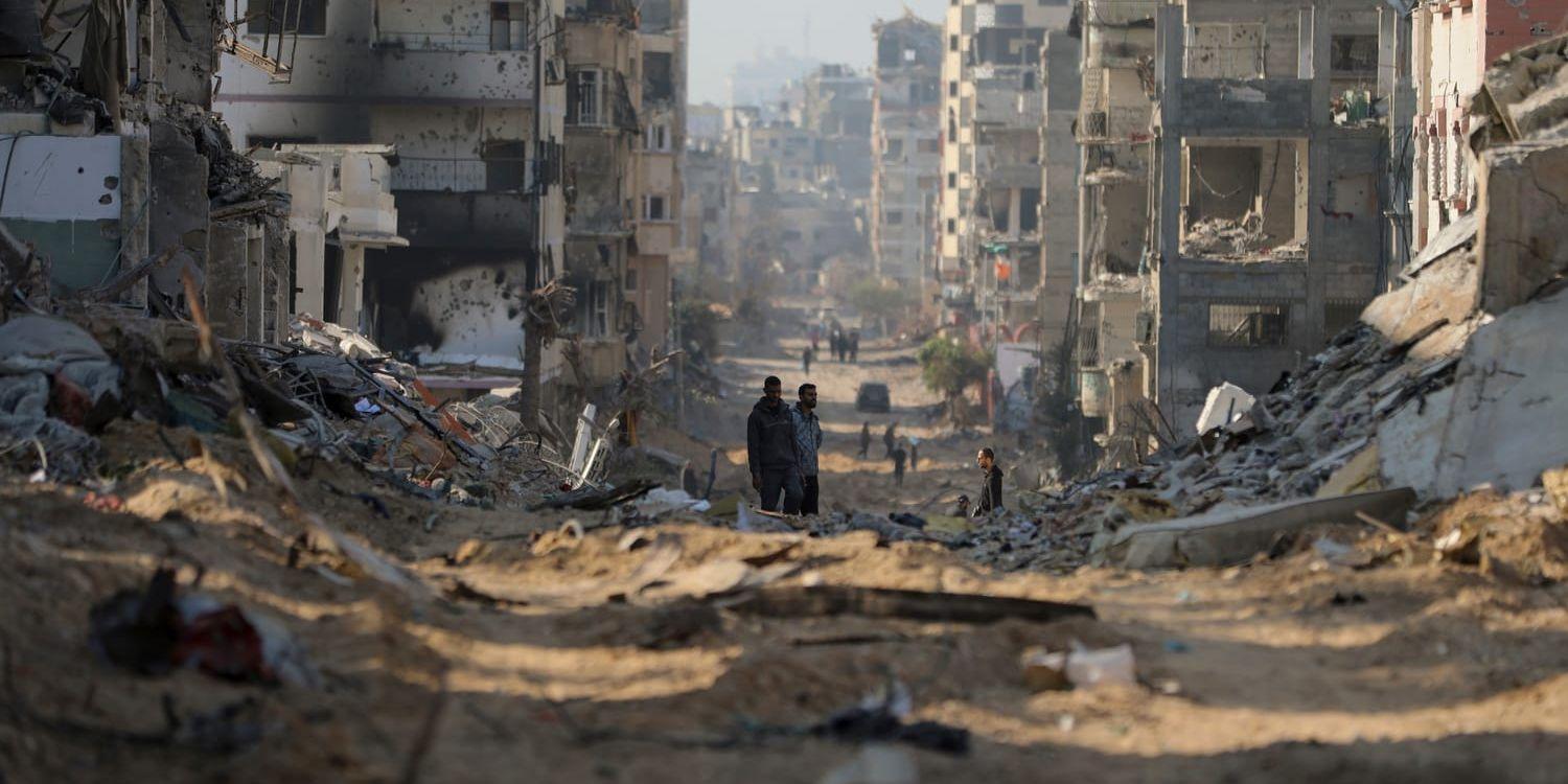 Palestinier går mellan resterna av förstörda byggnader efter det israeliska bombningen på huvudvägen i Gaza City tisdagen den 2 januari 2024.