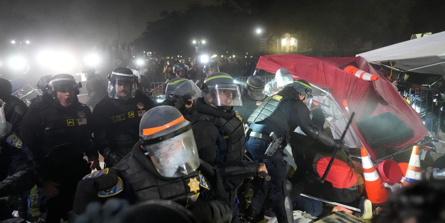 Polisen bryter igenom en barrikad som propalestinska demonstranter har satt upp utanför universitetet i Los Angeles.
