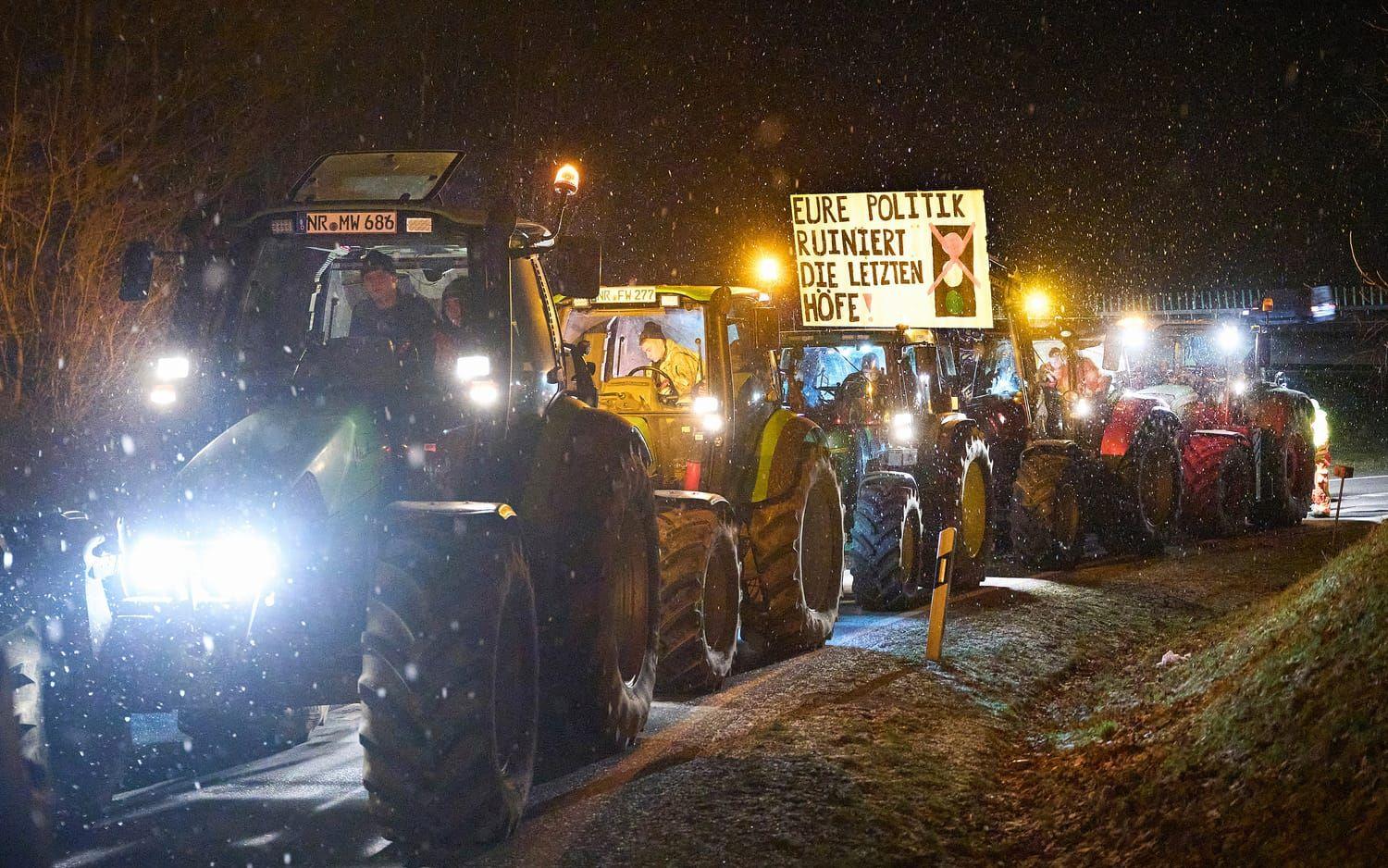 Tyska bönder blockerar en påfart till motorvägen A3 i vid Neustadt i förbundslandet Rheinland-Pfalz. En av traktorerna bär en skylt med texten ”Er politik förstör de sista bondgårdarna!”