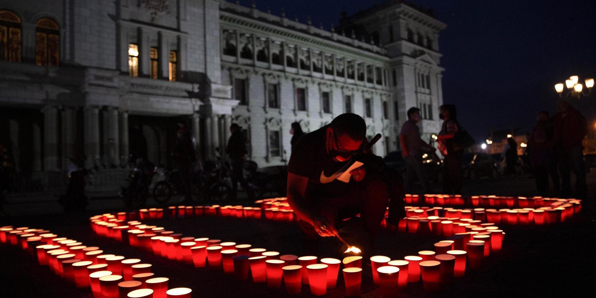 En man tänder ett ljus i Guatemala City för att hedra de tusentals människor som avlidit i covid-19.