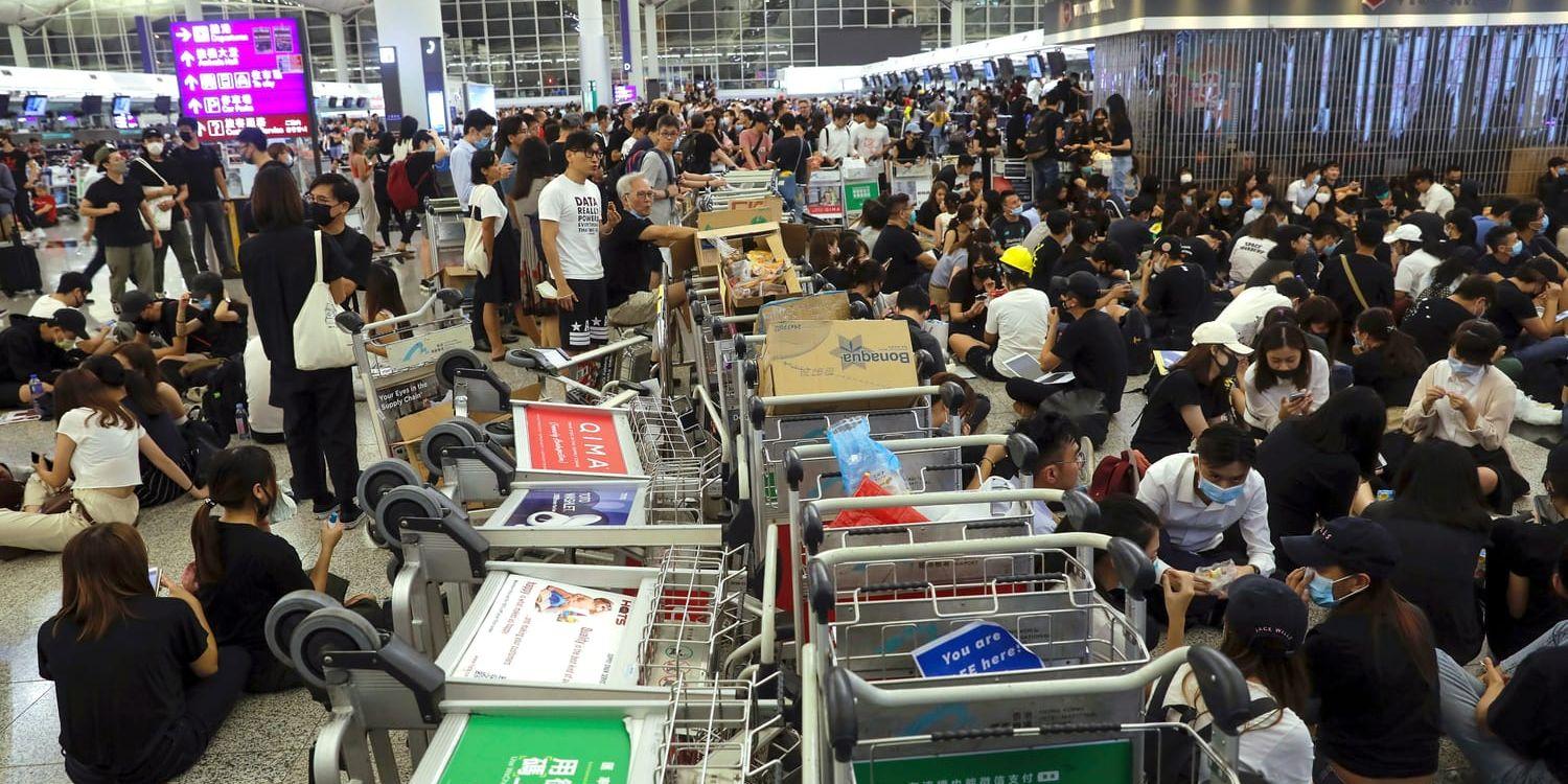 Protester på Hongkongs internationella flygplats. Demonstranter använder bagagevagnar för att stoppa resenärer. 