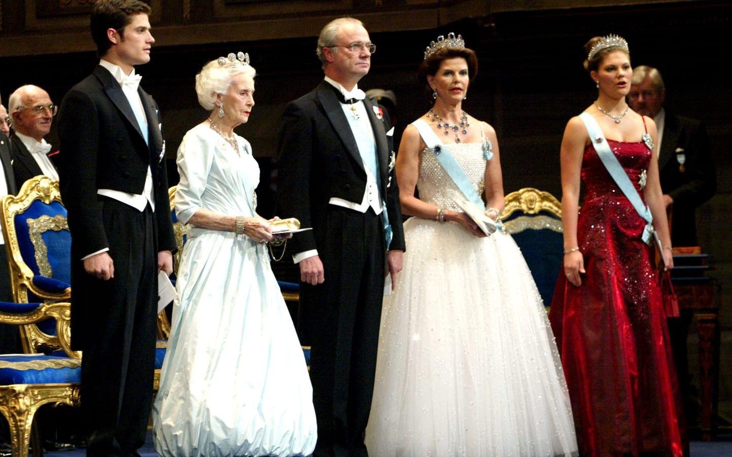 2001 bar drottningen en vit klänning med kjol av tyll fylld av kristaller och ett pärlbroderat liv. Prinsessan Madeleine bar klänningen på sin bröllopsmiddag år 2013. Klänningen är haute couture och från modehuset Nina Ricci.